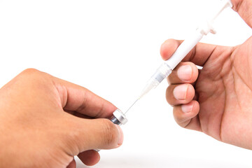 Selective focus hand push Syringe needle injected drill into medicine bottle on white background. Medical and treatment concept.