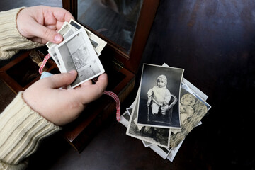 closeup female hand holding old vintage photos of 1940-1950, concept of family tree, genealogy,...