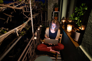 woman with laptop and dog on a terrace at home on a summer night