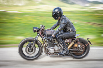 Fototapeta na wymiar Biker ride his rat motorbike on a green desolated plateau