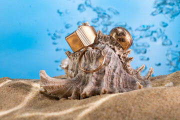Obraz premium golden ring underwater on the sand next to the seashells