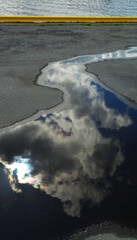 Rainwater poured into the dock in the harbor and reflects the blue sky and clouds, Bergen, Norway