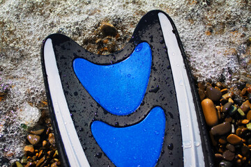 Swimming fin on the seashore. The wave is visiable. Flat lay, summer holidays, vacation and travel concept.