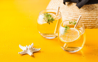 Summer background. Straw hat, refreshing lemonade, starfish on a yellow background. Copy space.