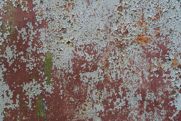 Fragment of an old steel wall. Remnants of layers of brown primer and gray paint have remained on the surface. There are rusted areas. Background. Texture.