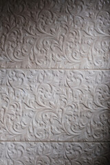 Fragment of textured beige tiles in the bathroom with floral pattern