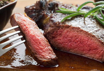 medium roast rib-eye steak on wooden plate with pepper and salt