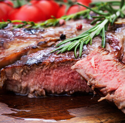 sliced beef steak with herbs and tomatoes on wooden desk