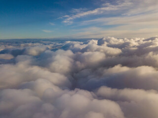 Naklejka na ściany i meble Aerial high flight above the clouds at sunrise.