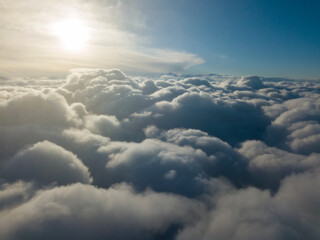 Naklejka na ściany i meble Aerial high flight above the clouds at sunrise.