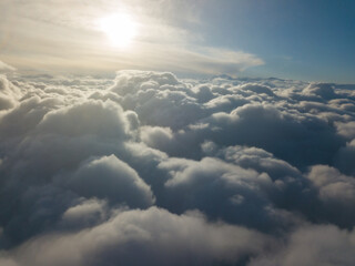 Aerial high flight above the clouds at sunrise.