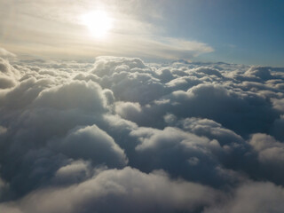 Aerial high flight above the clouds at sunrise.