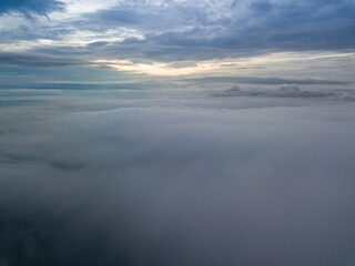 Fototapeta na wymiar Aerial high flight above the clouds. The rays of the rising sun break through the clouds.