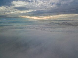 Aerial high flight above the clouds. The rays of the rising sun break through the clouds.