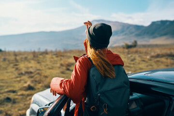 woman near cars gesturing with her hands on nature in the mountains autumn backpack travel tourism