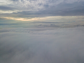 Aerial high flight above the clouds. The rays of the rising sun break through the clouds.
