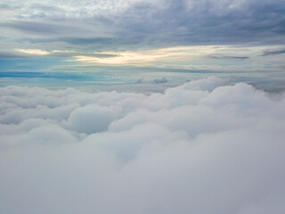 Aerial high flight above the clouds. The rays of the rising sun break through the clouds.