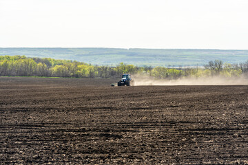 A blue tractor works on a field on a spring morning.