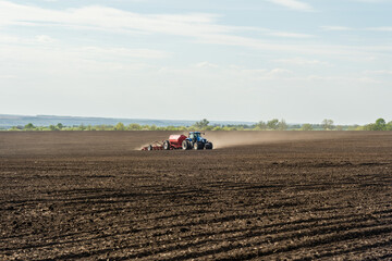 A tractor with cultivator plowing on morning.