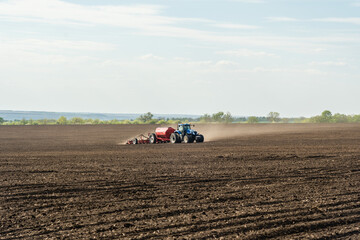 A tractor with cultivator plowing on morning.