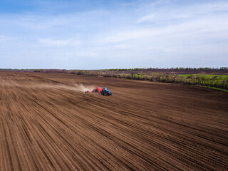 Aerial view of plowing fields by tractor and blue sky