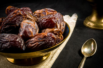 Big luxury dried date fruit in bowls on a linen napkin, kurma ramadan kareem concept, close up.