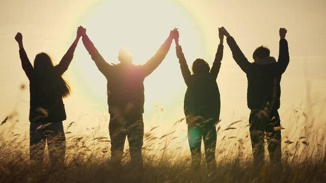 Happy family holding hands together at sunset. Silhouette park. teamwork of family people in business. Success happy team people silhouette. Family holding hands together at sunset in the park.