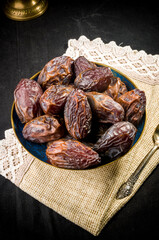 Big luxury dried date fruit in bowls on a linen napkin, kurma ramadan kareem concept, close up.