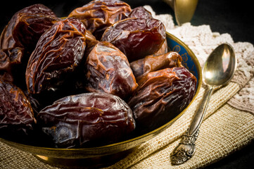 Big luxury dried date fruit in bowls on a linen napkin, kurma ramadan kareem concept, close up.