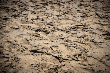Closeup surface of sand dune in dark mood. The field is roughly tramped and there are many cracks on the surface.