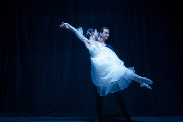Graceful balerina in image of ghost bride with patner in art ballet performance isolated over dark background. © Lustre Art Group 
