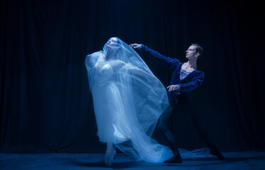 Graceful balerina in image of ghost bride with patner in art ballet performance isolated over dark background. © Lustre Art Group 