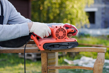 Close up of carpenter using electric sander for restoration of old chair