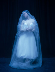 Young graceful balerina in image of ghost bride in art performance isolated on dark background in neon light. © Lustre Art Group 
