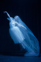 Loneliness. Young graceful beautiful woman, balerina in white wedding dress in art performance.