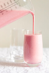 Strawberry milkshake pouring in the glass.