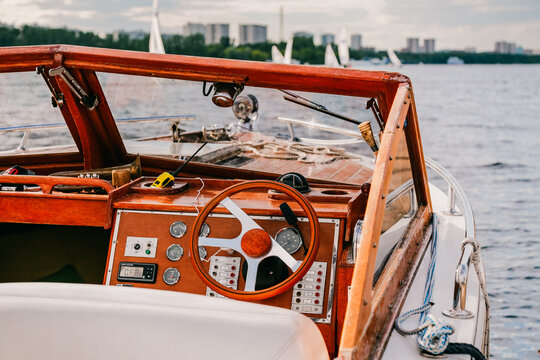 Close-up of beautiful vintage yacht for tourist in marina. Navigation implement design, buttons, dials, glass windows. City landscape, buildings on river. Romantic holiday vacation. Private journey. 