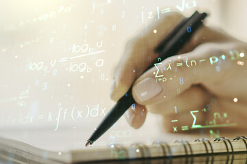 Creative scientific formula hologram with woman hand writing in notepad on background, research...