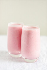 Two glasses of strawberry milkshake on table.