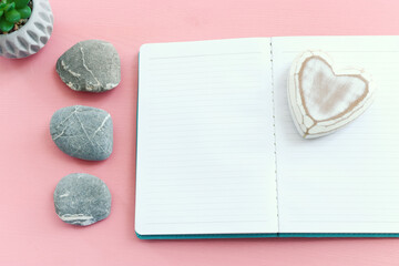 Empty open notebook and zen pebbles on pastel wooden background. copy space for text