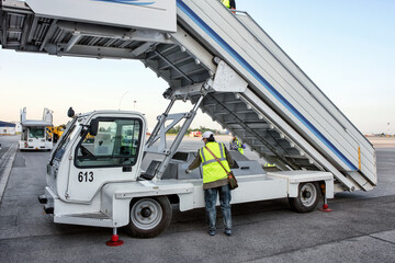 A worker waiting for an aircraft landing by a plane ladder at the airport.
