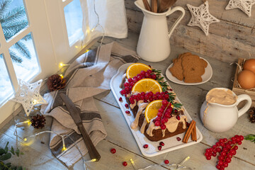 Traditional christmas cinnamon cake decorated with fruits and spekulatius cookies cream on a kitchen countertop.