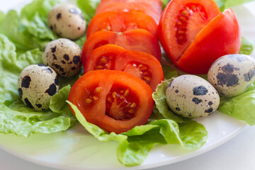 washed tomatoes on a plate with lettuce leaves and quail eggs