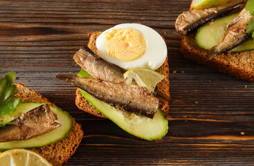  3 sandwiches with rye bread, sprats,  cucumber and boiled eggs,