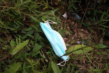 green medical mask thrown on the grass