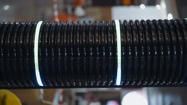 Dark corrugated plastic tube with glowing led rings changing colors as decorative element on blurred background in shopping mall super closeup