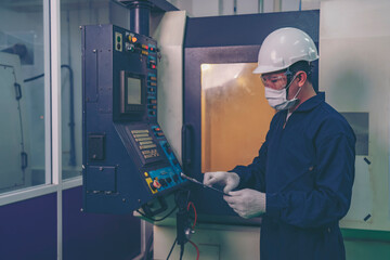 Male industrial engineer or technician worker using control machine operating control CNC machinery at factory Industrial.