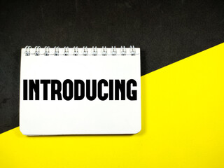 Business concept. Notebook with text INTRODUCING on black and yellow background