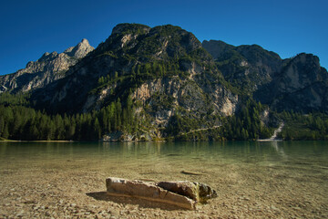 Beautiful reflections in the crystal clear water of Pragser Wildsee Lake Braies with mountains and forest in the background in Tyrol, Northern Italy. 
