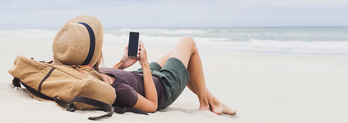 Young woman lying with smart phone on beach panoramic banner. Relaxation and freelance concept	